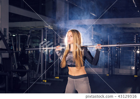 sport, fitness, training and happiness concept - sporty woman with barbell in gym 43129316