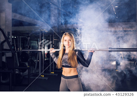sport, fitness, training and happiness concept - sporty woman with barbell in gym 43129326