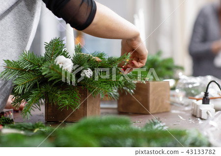 A woman decorates a Christmas arrangement with candles. Hands close-up. Master class on making 43133782