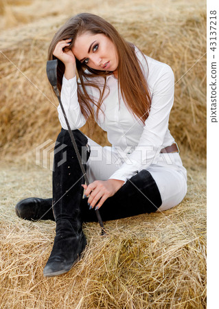 rider woman with whip is sitting on hay rider woman with whip is sitting on hay 43137218