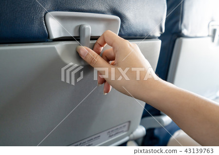 Hand of female passenger try to open a tray 43139763
