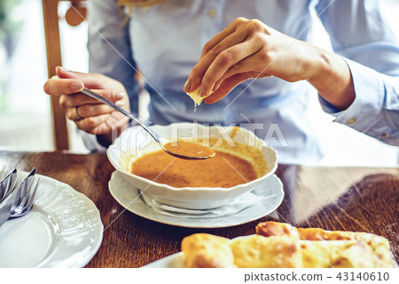 Woman squishing lemon in green peas soup Woman squishing lemon in green peas soup 43140610