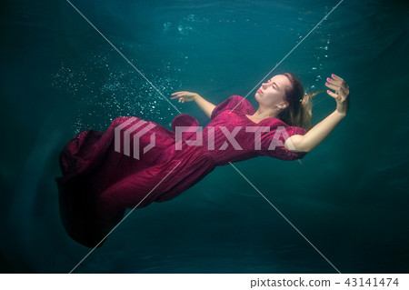 Woman in red dress underwater. 43141474