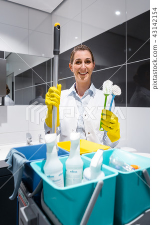 Janitor or charlady with her work tools looking at camera in toilet 43142154