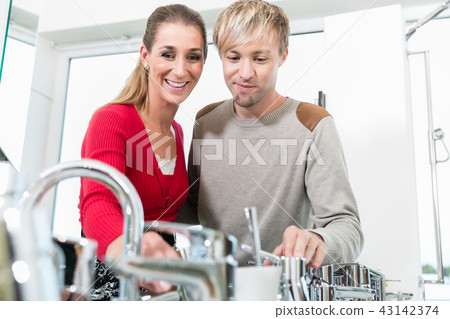 Happy couple choosing a new faucet in a modern sanitary ware shop Happy couple choosing a new faucet in a modern sanitary ware shop 43142374