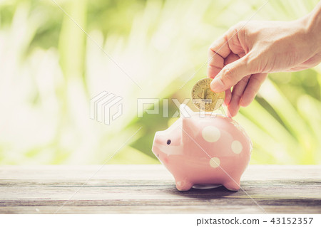 Saving golden bitcoin in piggy bank with hand 43152357