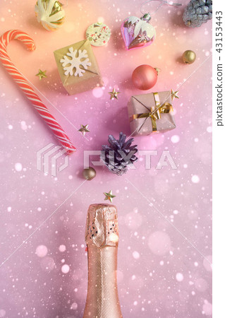 Champagne bottle with different christmas decoration on pink background. New year concept. 43153443