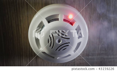 Low angle shot: The smoke detector is triggered by a trickle of dum, the red indicator lights up 43159226