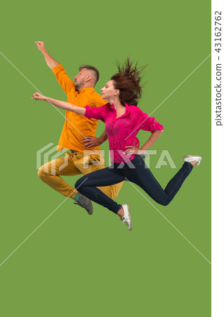 Freedom in moving. Pretty young couple jumping against green background 43162762