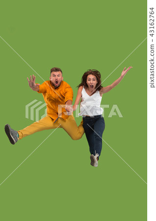 Freedom in moving. Pretty young couple jumping against green background 43162764