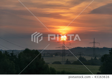 Red rising sun on top of an electric pole 43163616