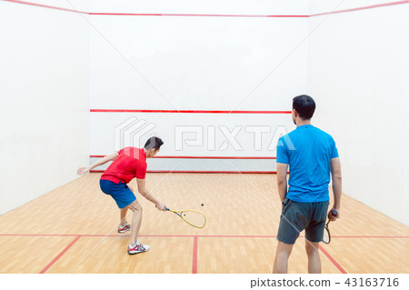 Rear view of two competitive young men playing squash game Rear view of two competitive young men playing squash game 43163716