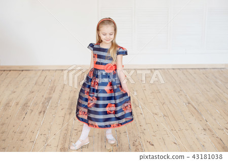 Attractive little girl in colorful dress spinning around indoors 43181038