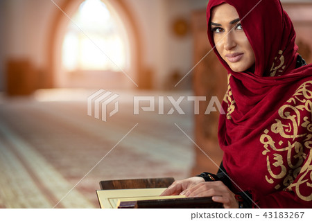 Young muslim woman praying in mosque with quran Young muslim woman praying in mosque with quran 43183267