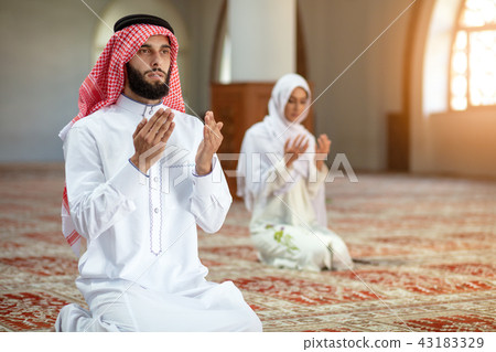 Muslim man and woman praying in mosque Muslim man and woman praying in mosque 43183329