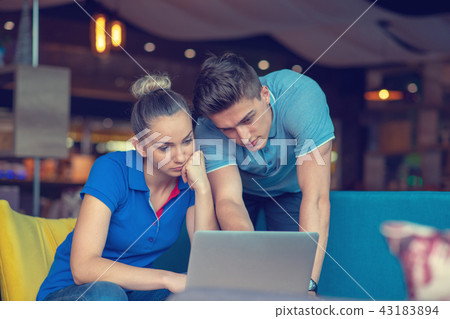 Group of two coworkers working comparing forecasting graphics in a coffee shop Group of two coworkers working comparing forecasting graphics in a coffee shop 43183894