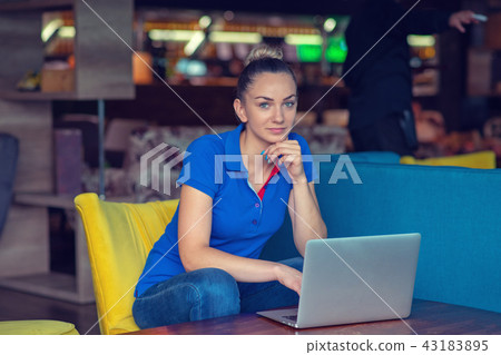 Young beautiful woman studying or working with laptop computer in neighborhood cafe 43183895