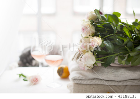 Two glasses of wine and a lot of winter warm clothes at home near the window. Cat, large bouquet of Two glasses of wine and a lot of winter warm clothes at home near the window. Cat, large bouquet of 43188133