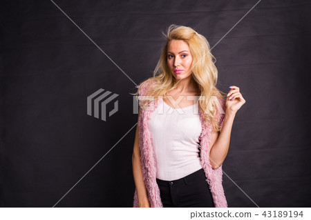 Modeling, fashion, people concept- young serious blonde in pink coat over the black background with Modeling, fashion, people concept- young serious blonde in pink coat over the black background with 43189194