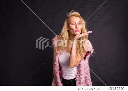 Fashion and beauty concept - Portrait of young blonde woman in kiss pose on black background with Fashion and beauty concept - Portrait of young blonde woman in kiss pose on black background with 43189201