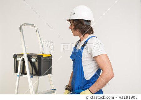 Construction, building and workers concept - Curly haired builder with toolbox and white helmet in 43191905