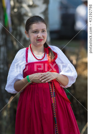 Young woman in Russian folk bright scarlet dress for Slavic holiday 43192798