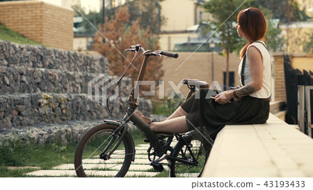 Redhaired woman cyclist making selfie on mobile phone with bike. Woman bicycling Redhaired woman cyclist making selfie on mobile phone with bike. Woman bicycling 43193433