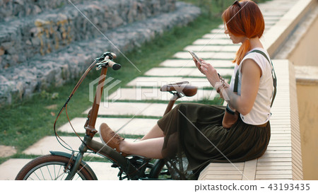 Redhaired woman cyclist making selfie on mobile phone with bike. Woman bicycling Redhaired woman cyclist making selfie on mobile phone with bike. Woman bicycling 43193435