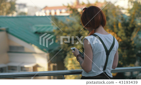 Young redhaired woman riding bicycle in city. Woman with mobile phone Young redhaired woman riding bicycle in city. Woman with mobile phone 43193439