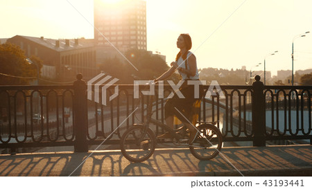 Red haired woman riding a bicycle on background sunlight in city 43193441