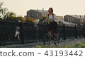 Red haired woman riding bicycle in city on background facade building 43193442