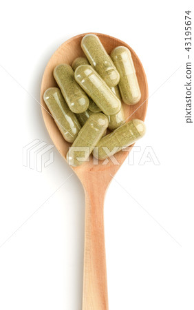 Wooden spoon full of herbal capsules 43195674