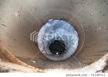 frozen water surface and ice hole in concrete well 43196311