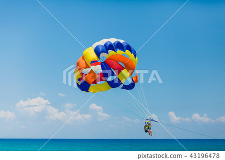 Couple of tourists flying on a colorful parachute 43196478