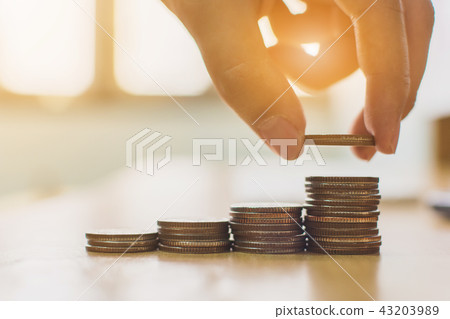 Hand putting coin stack step staircase on desk 43203989