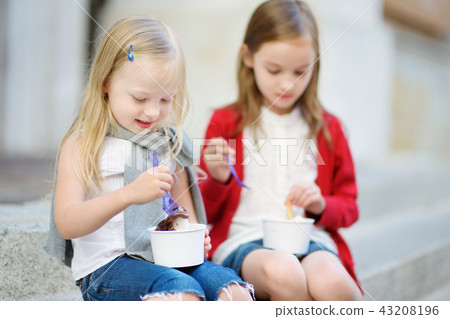 Two cute little sisters eating ice-cream  43208196