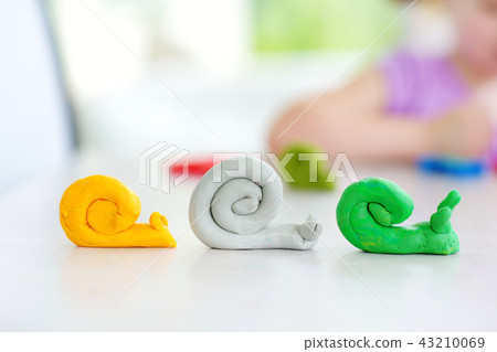 Cute little girl having fun with modeling clay at a daycare. Creative kid molding at home. Cute little girl having fun with modeling clay at a daycare. Creative kid molding at home. 43210069