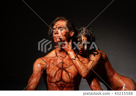 Bloodstained naked couple shot against black wall 43215588