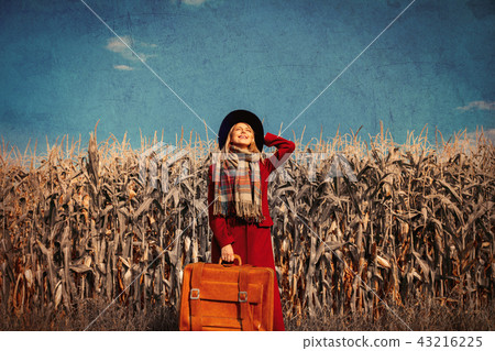 girl coat with suitcase on a rural road near cornfield girl coat with suitcase on a rural road near cornfield 43216225