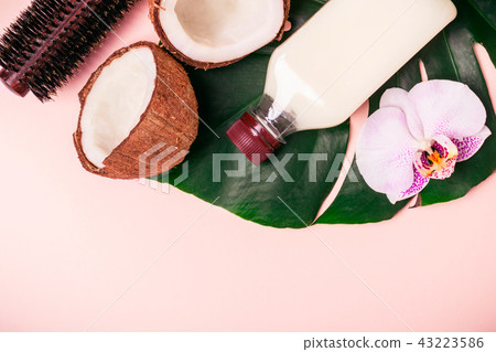 Coconut oil and halves of fresh coconut on a pink background. Hair care spa concept Coconut oil and halves of fresh coconut on a pink background. Hair care spa concept 43223586