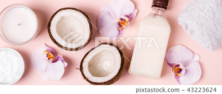 Coconut oil and halves of fresh coconut on a pink background. Hair care spa concept 43223624