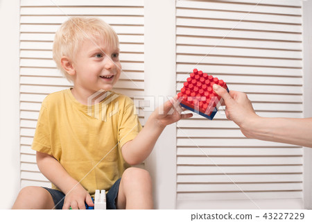 Blond boy takes a designer from a woman's hand 43227229