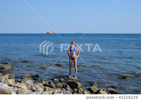 A beautiful girl in a blue bikini walks the pier to the sea. Marine concrete pier. Jumping into the A beautiful girl in a blue bikini walks the pier to the sea. Marine concrete pier. Jumping into the 43228229