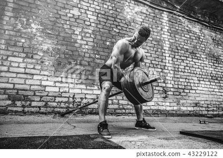 Athletic man working out with a barbell. Strength and motivation. Exercise for the muscles of the Athletic man working out with a barbell. Strength and motivation. Exercise for the muscles of the 43229122