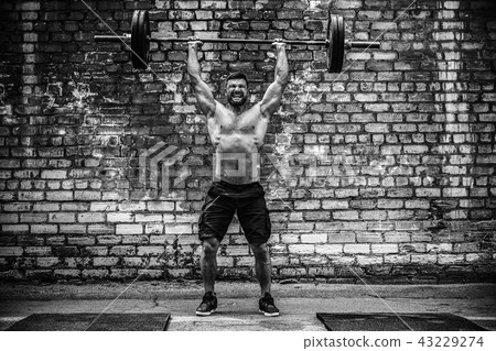Muscular fitness man doing deadlift a barbell over his head in outdoor, street gym. Functional 43229274
