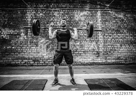 Muscular fitness man doing deadlift a barbell over his head in outdoor, street gym. Functional 43229378