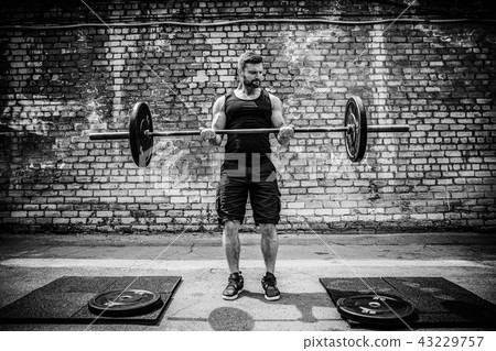 Muscular fitness man doing deadlift a barbell over his head in outdoor, street gym. Functional 43229757