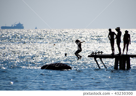 Silhouettes of people jumping from the sea pier. Rest on the sea beach 43230300