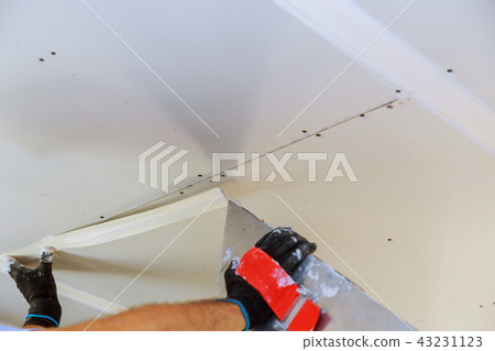 Hand with a spatula plaster on a wall 43231123