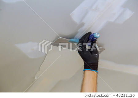 Man aligning wall with spatula working with putty 43231126